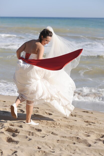 Feliz novia joven divertida caminando en una playa de mar