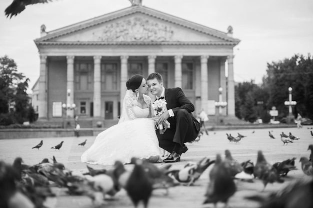 Feliz novia y novio besándose entre palomas