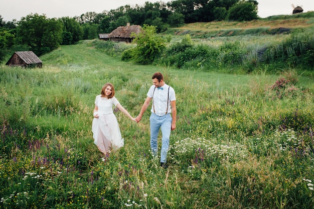 Feliz novia y el novio caminando sobre la hierba verde