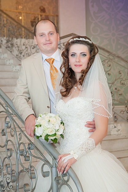 Feliz novia y el novio en la escalera en el paseo de bodas