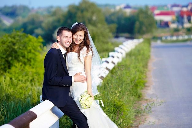 Feliz novia y el novio riendo sonriendo en la carretera el día de la boda.