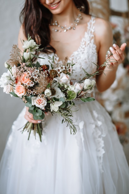 Feliz novia en un vestido de novia con un ramo de flores en sus manos