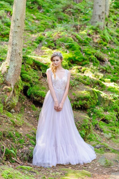 Feliz novia en un vestido de novia rosa. Ceremonia de boda de estilo boho en el bosque.