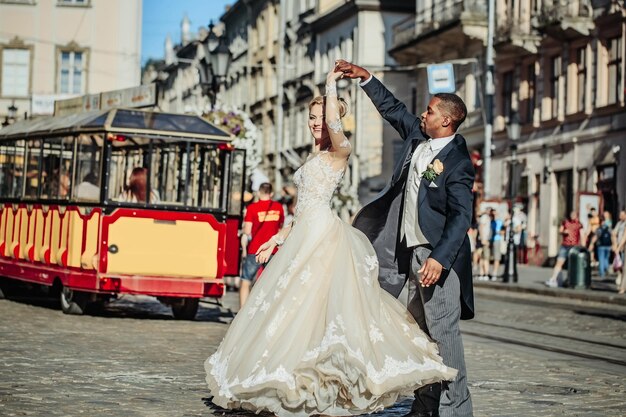 Feliz novio afroamericano y linda novia bailando en la calle