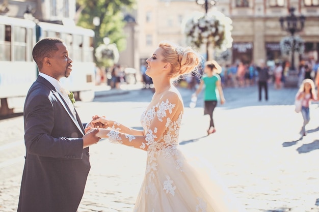 Feliz novio afroamericano y linda novia bailando en la calle