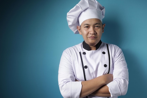 Feliz y orgulloso chef asiático sonriendo a la cámara con los brazos cruzados