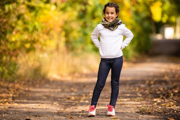 ¡Feliz otoño! Dulce niña jugando con hojas en un parque de otoño. Copie el espacio, hojas caídas.