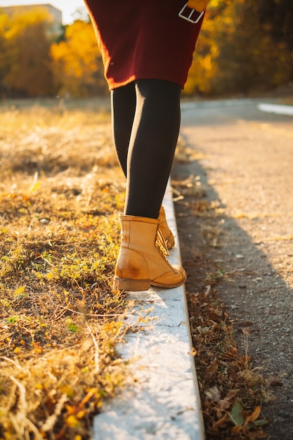 Feliz otoño hola otoño temporada de otoño piernas femeninas con botas amarillas caminando por la acera con otoño