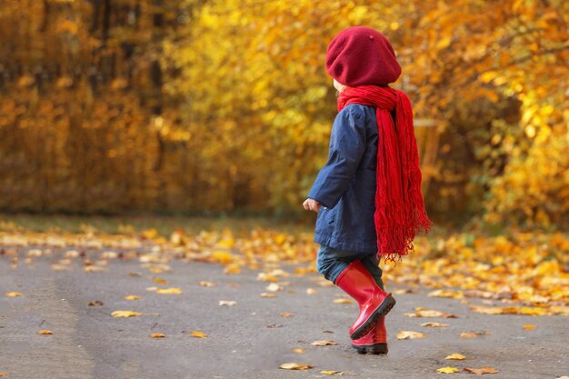 Feliz otoño La niña se ríe y corre en chanclos por el parque otoñal