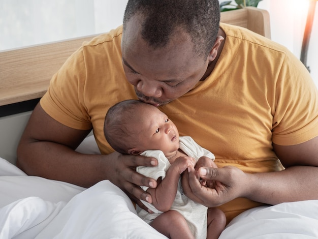 Feliz padre afroamericano con un hijo recién nacido de dos semanas en la guardería