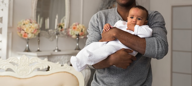 Feliz padre afroamericano sosteniendo al bebé sonriente.