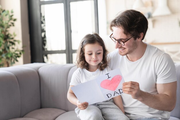 Feliz padre amoroso y su linda hija leyendo tarjetas de felicitación celebrando el día del padre