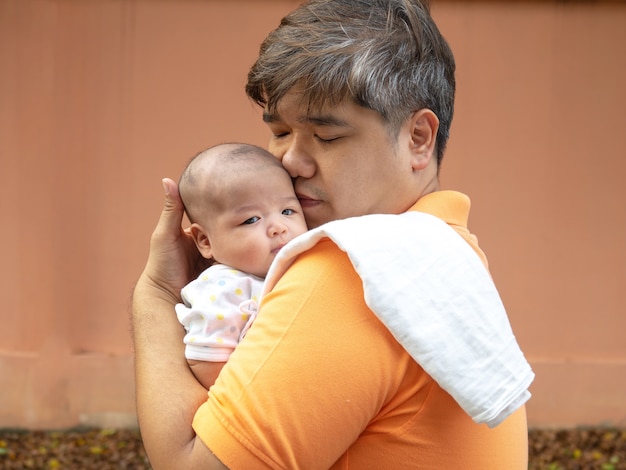 feliz padre de Asia sosteniendo a su bebé dulce recién nacido. El padre abraza a su bebé con amor