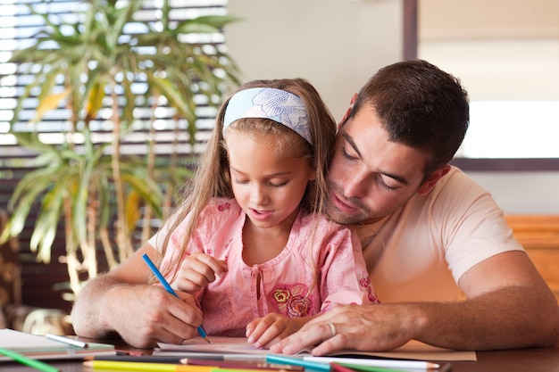 Feliz padre ayudando a su hija a hacer los deberes