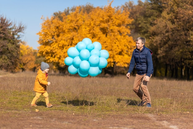 Feliz padre disfruta pasar el día libre con su hijo en el parque de otoño Jugar con globos