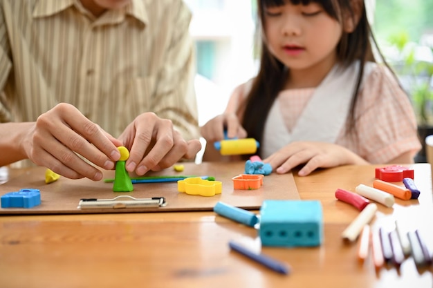 Feliz padre e hija asiáticos disfrutan moldeando arcilla colorida o jugando masa juntos en casa