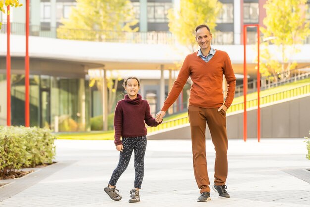 Feliz padre e hija caminando juntos en el parque en un día de otoño.