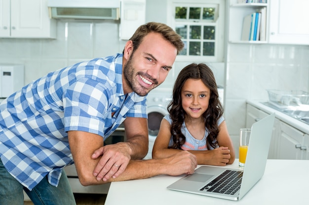 Feliz padre e hija con laptop en cocina