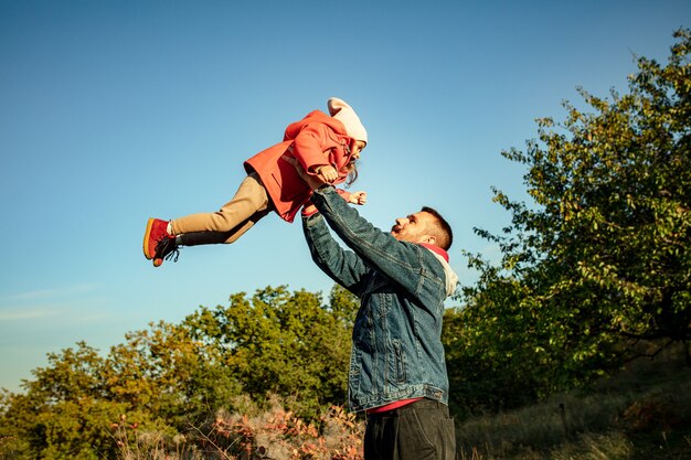 Foto feliz padre e hija linda caminando por el sendero del bosque en un día soleado de otoño