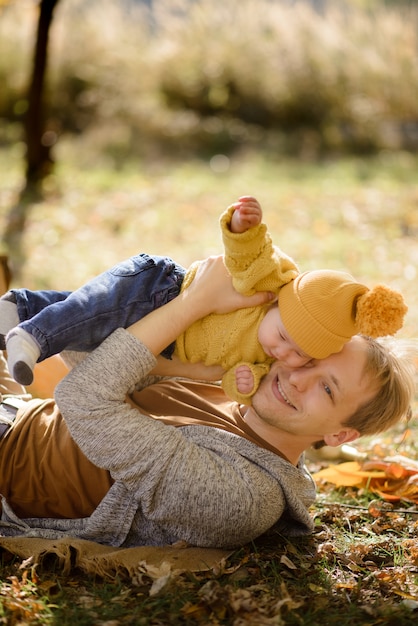 Feliz padre e hija en otoño parque acostado sobre hojas amarillas