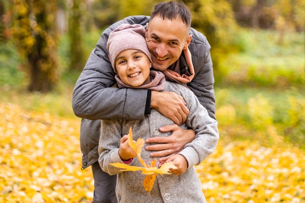 Feliz padre e hija en el parque de otoño en hojas amarillas