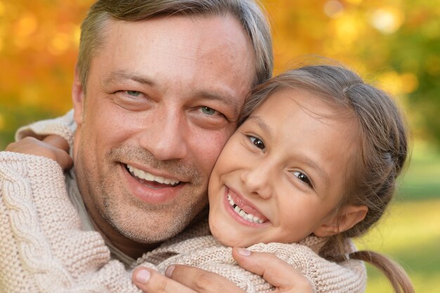 Feliz padre e hija posando al aire libre en otoño