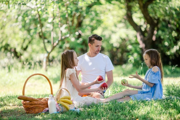 Feliz padre e hijas pequeñas se relajan junto al lago