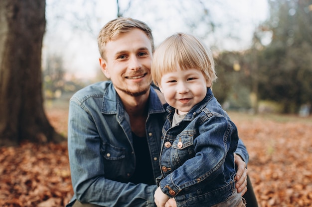 Feliz padre e hijo divirtiéndose en el parque otoño