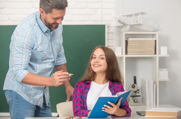 Feliz padre e hijo estudian en la escuela con un libro sobre educación de fondo de pizarra