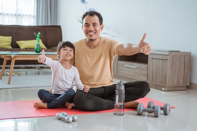 Feliz padre e hijo haciendo ejercicio juntos. retrato de entrenamiento familiar saludable en casa. hombre y su hija deporte