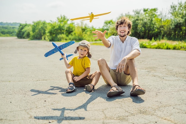 Feliz padre e hijo jugando con un avión de juguete contra el antiguo fondo de la pista Viajando con el concepto de niños