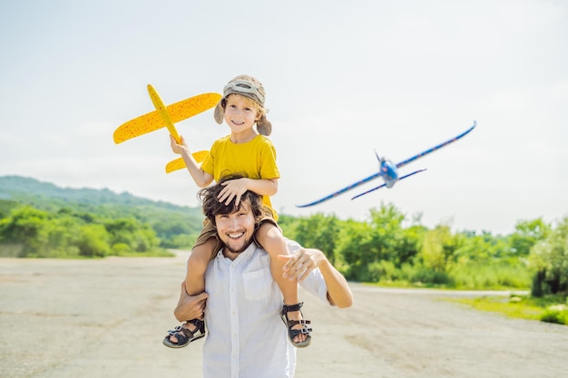 Feliz padre e hijo jugando con un avión de juguete contra el antiguo fondo de la pista Viajando con el concepto de niños