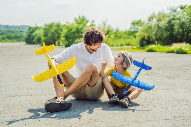 Feliz padre e hijo jugando con un avión de juguete contra el antiguo fondo de la pista Viajando con el concepto de niños