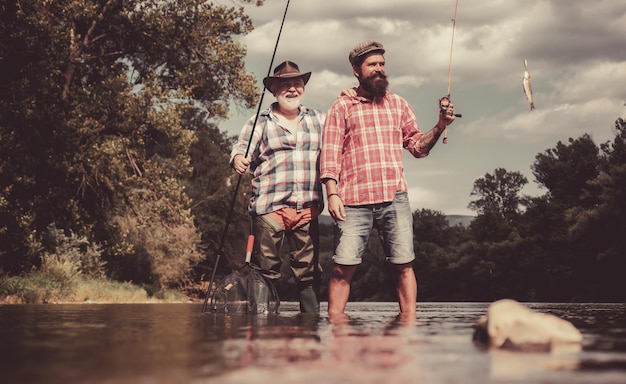 Foto feliz padre e hijo juntos pescando en un día de verano bajo un hermoso cielo en el río pesca con mosca mosca