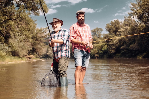 Feliz padre e hijo juntos pescando en verano bajo un hermoso cielo en el río Pescador y t