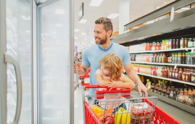 Feliz padre e hijo mirando el producto en la tienda de comestibles