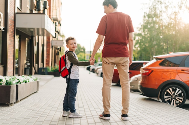 Feliz padre e hijo niño yendo a clases padre llevar niño niño a la escuela en alumno de primer grado de