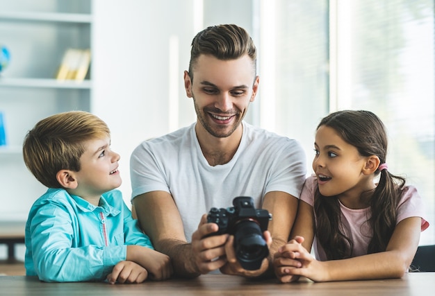 El feliz padre e hijos con una cámara sentados en la mesa.