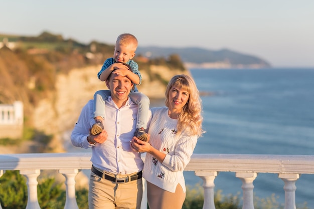 Feliz padre de familia, madre, hijo, camina con diversión a lo largo del borde del mar al atardecer, surfea en el Mar Negro