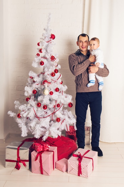 Feliz padre de familia y niño bebé con árbol de Navidad