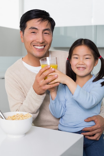 Feliz padre con hija desayunando en la cocina