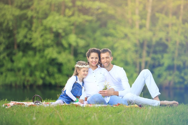 Feliz padre de una hija y una madre embarazada en un picnic.