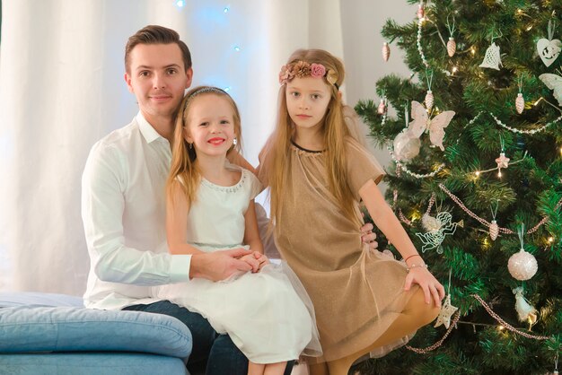 Feliz padre con hijos cerca del árbol de Navidad en la víspera de Navidad