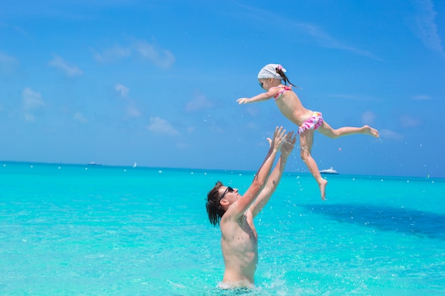 Feliz padre juega con hija pequeña en mar perfecto