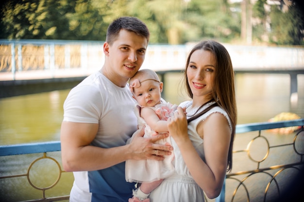 Feliz padre y madre caminando con linda niña en el parque