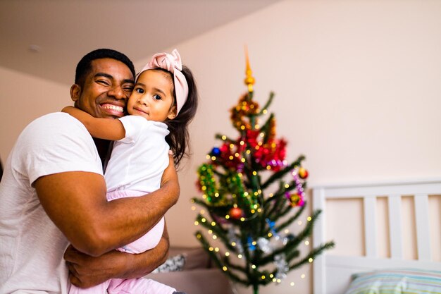 Feliz padre de raza mixta y hermoso niño en la feliz mañana de Navidad en el dormitorio