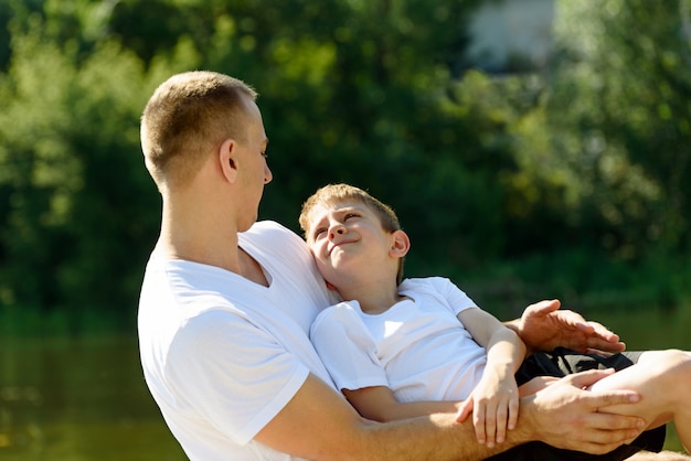 Feliz padre con su pequeño hijo en brazos al aire libre