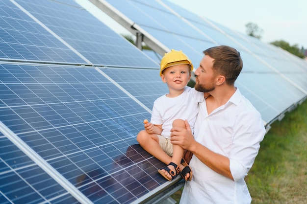 Feliz padre y su pequeño hijo caminan cerca de los paneles solares El concepto de energía verde