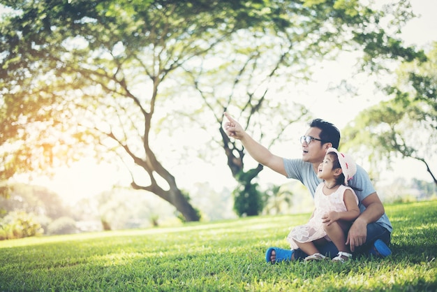 Feliz pai e filha apontando com o dedo e olhando algo no parque
