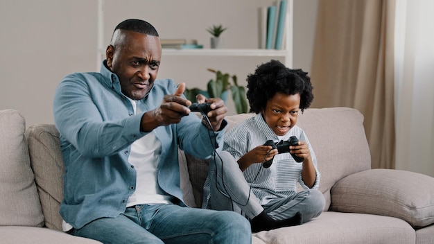 Feliz pai e filha da família afro-americana se divertem juntos pai jogando videogame em